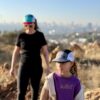 All smiles mother and daughter hiking in the fields around Johannesburg wearing trail caps in teal / jade / gold and grey / black