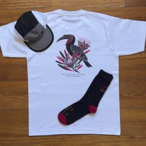 White shirt, black and red socks wrapped and a trail cap in grey and black on a wooden table